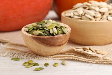 Photo of Bowls with pumpkin seeds on light wooden table