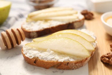 Delicious ricotta bruschettas with pear and walnut on white table, closeup