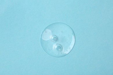 Sample of cosmetic serum on light blue background, top view