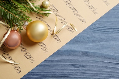 Flat lay composition with Christmas decorations and music sheets on blue wooden table. Space for text