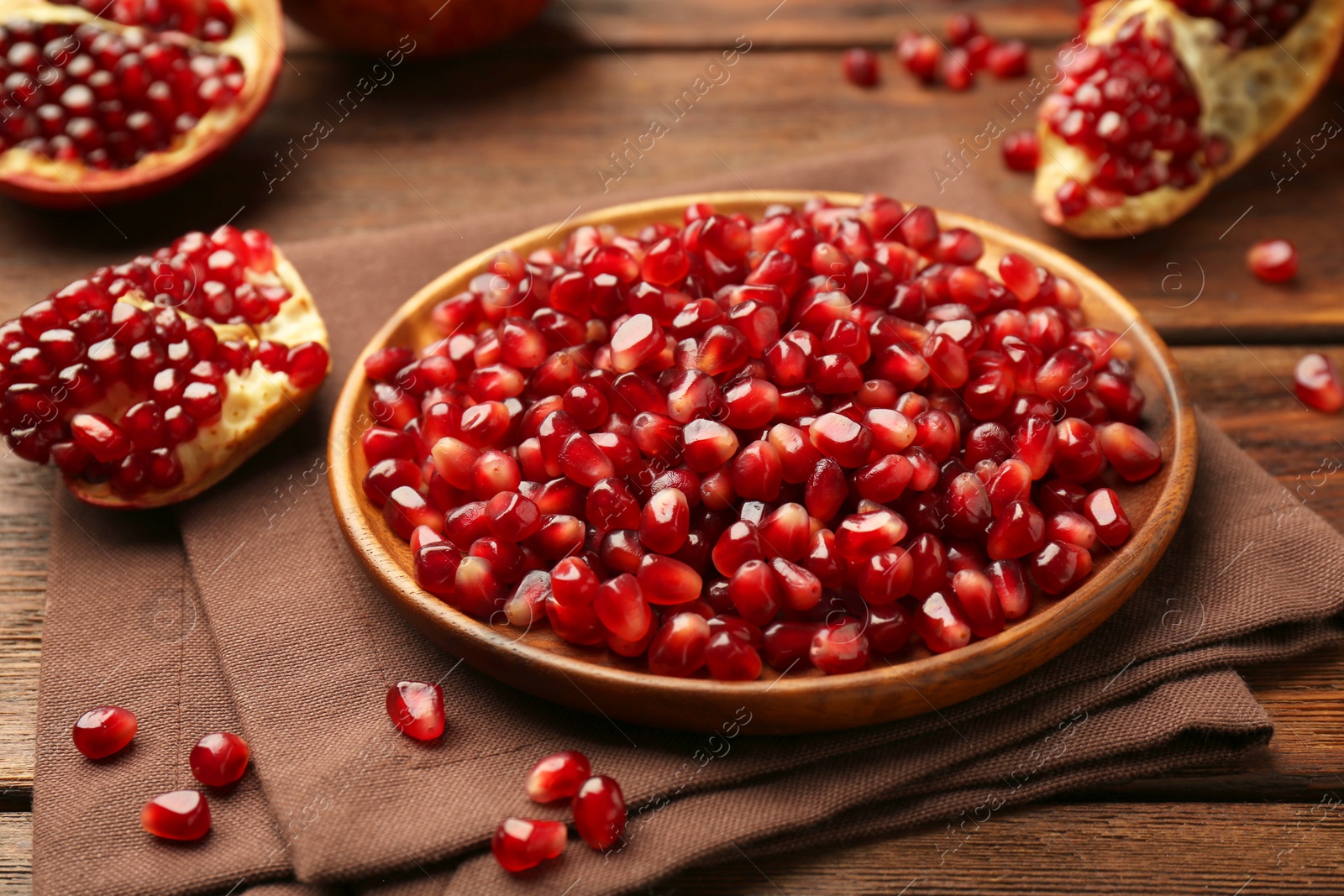 Photo of Ripe juicy pomegranates and grains on wooden table