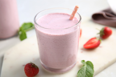 Photo of Tasty milk shake with strawberries and mint on white marble board