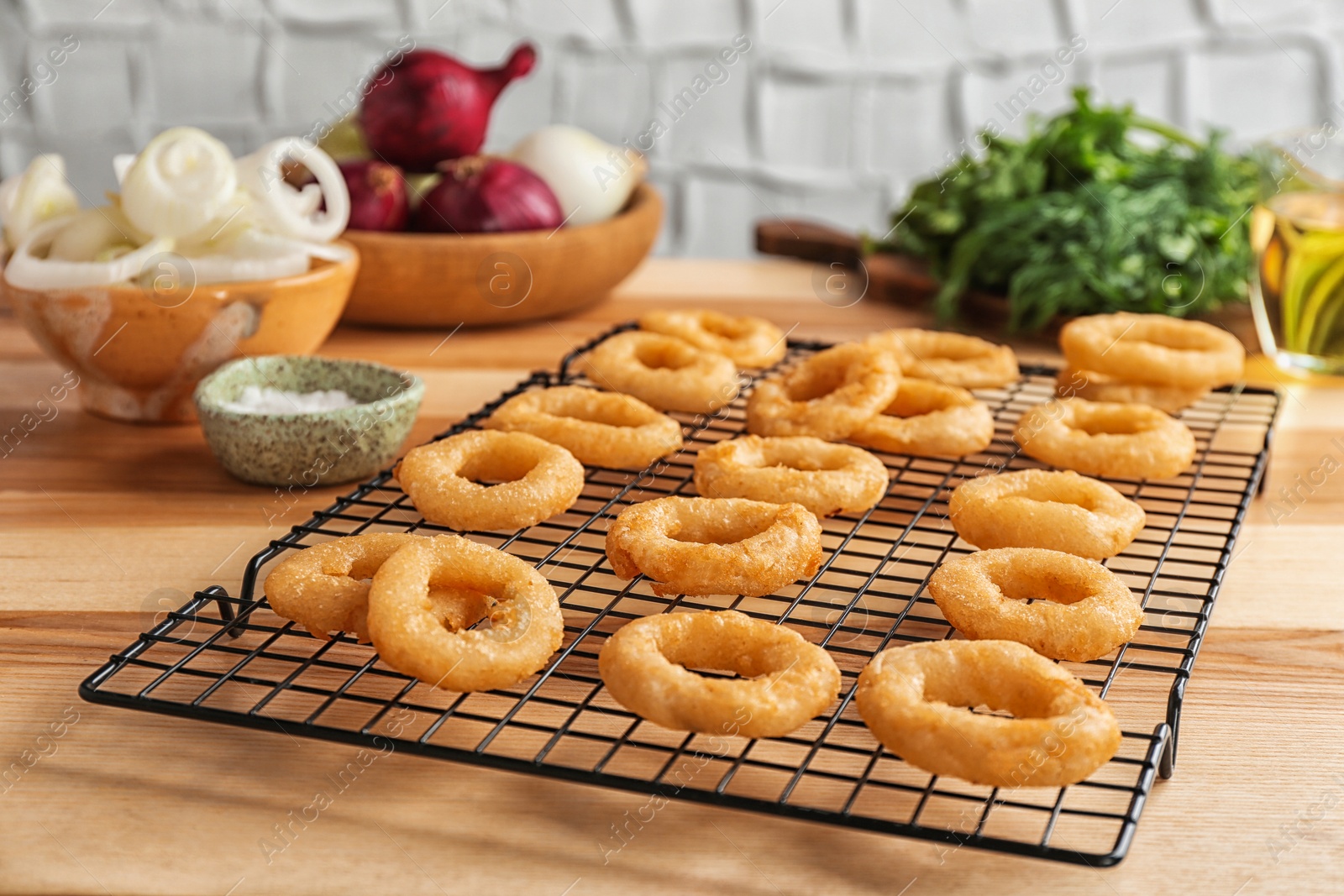 Photo of Cooling rack with tasty onion rings on table