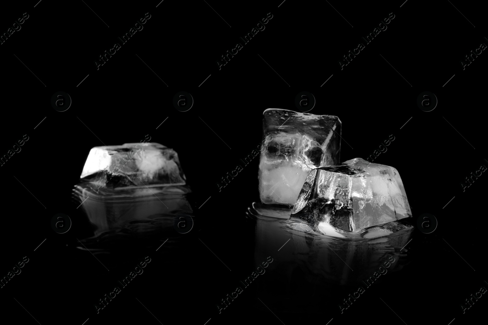 Photo of Three ice cubes on black mirror surface. Space for text