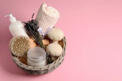 Spa gift set of different luxury products in wicker basket on pale pink background, space for text