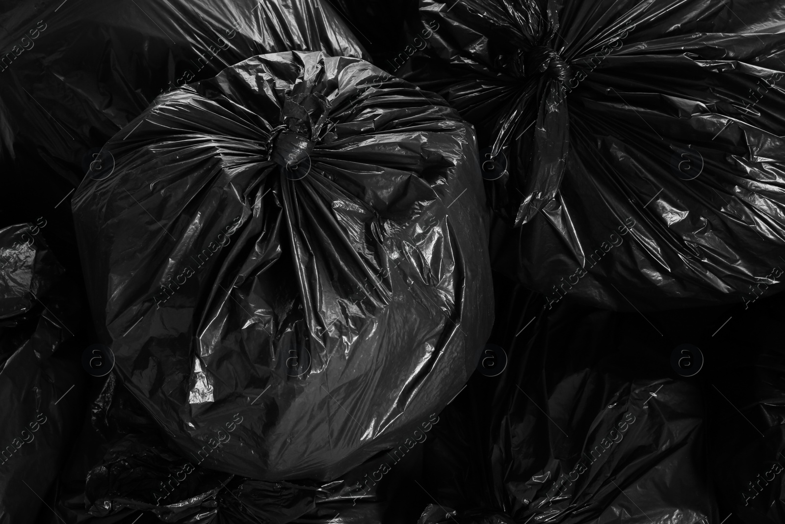 Photo of Black trash bags full of garbage as background, top view