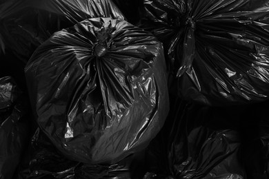 Photo of Black trash bags full of garbage as background, top view