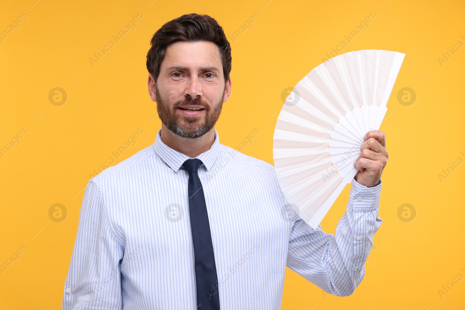 Photo of Happy man holding hand fan on orange background