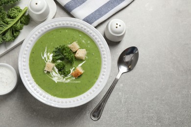 Tasty kale soup with croutons served on grey table, flat lay