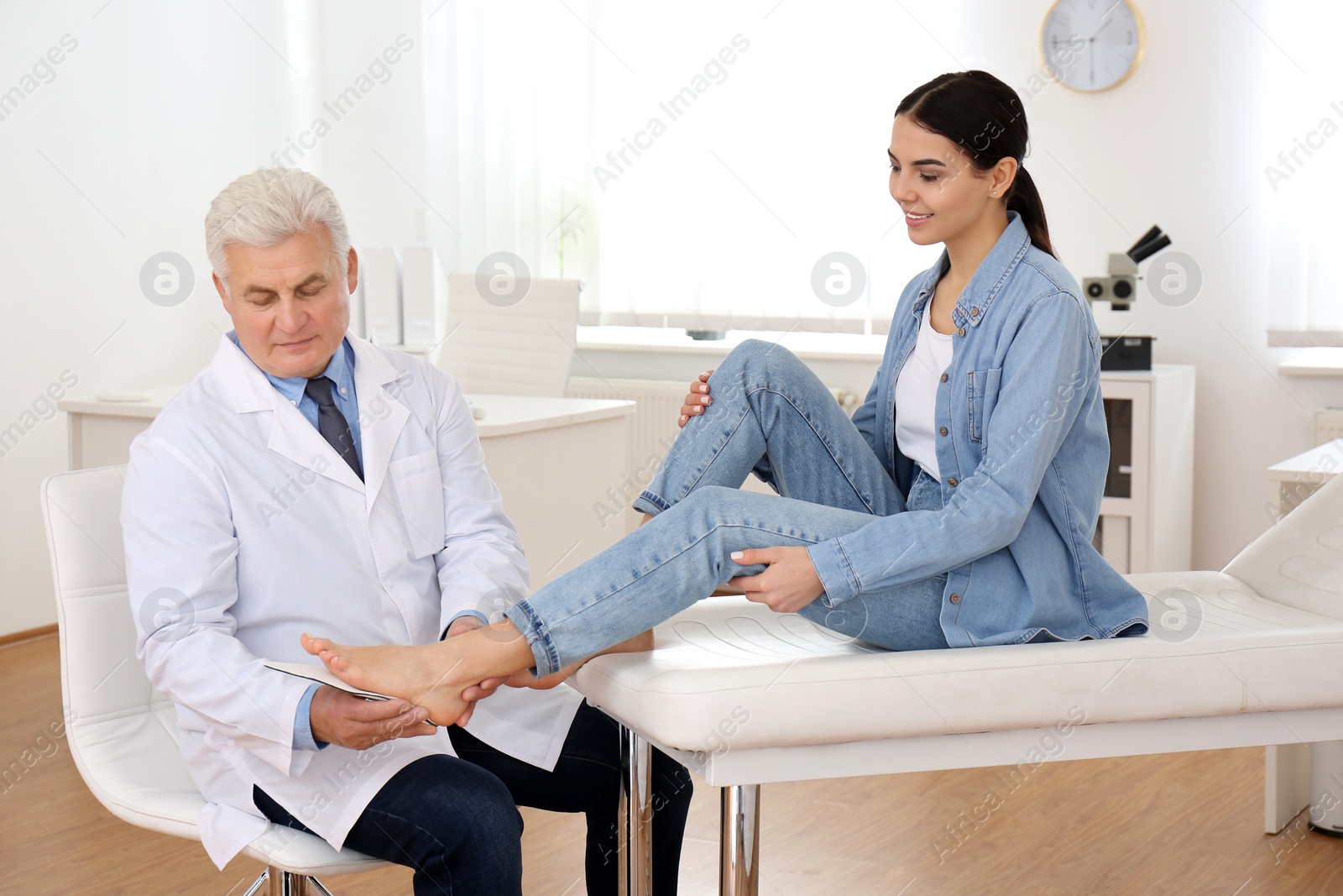 Photo of Male orthopedist fitting insole on patient's foot in clinic