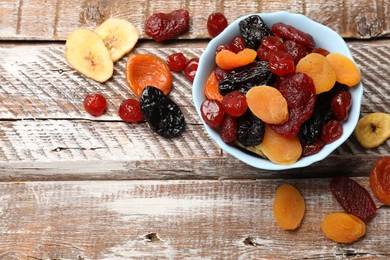 Photo of Mix of delicious dried fruits on wooden table, flat lay. Space for text