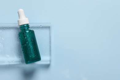 Photo of Bottle of cosmetic serum on light blue background, top view. Space for text