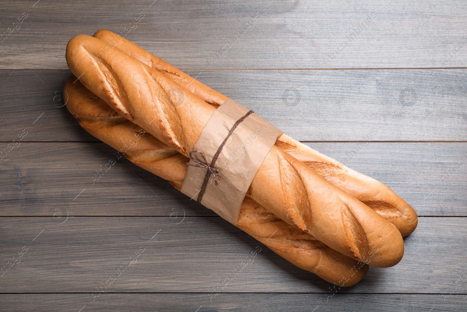 Photo of Bunch of tasty baguettes on wooden table, top view