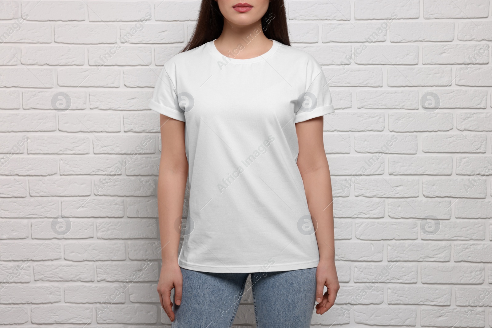 Photo of Woman wearing stylish T-shirt near white brick wall, closeup