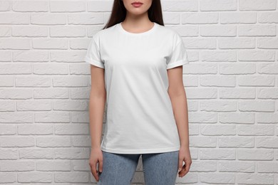 Woman wearing stylish T-shirt near white brick wall, closeup