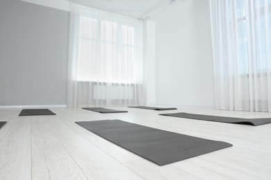 Photo of Spacious yoga studio with exercise mats, low angle view. Space for text