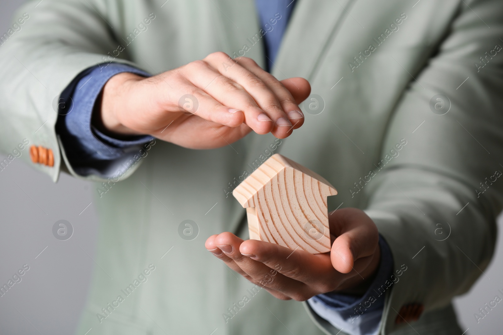 Photo of Male agent covering wooden house, closeup. Home insurance