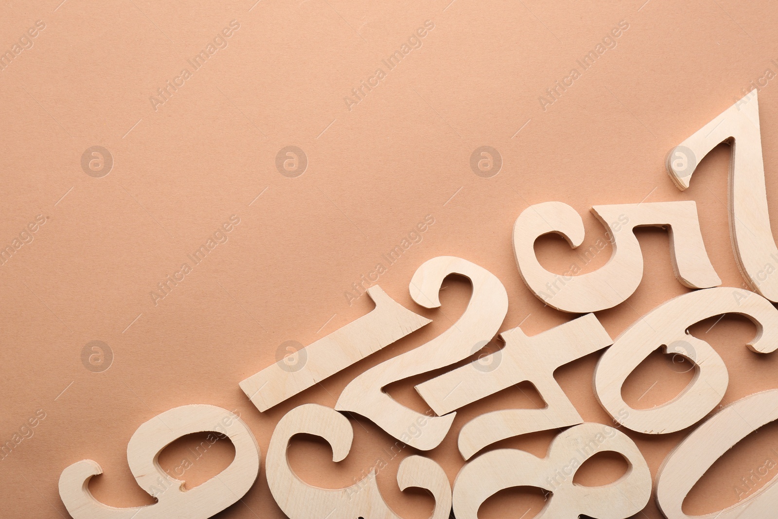 Photo of Wooden numbers on beige background, flat lay. Space for text