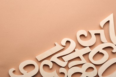 Photo of Wooden numbers on beige background, flat lay. Space for text