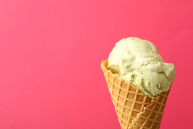 Delicious ice cream in waffle cone on pink background, closeup. Space for text