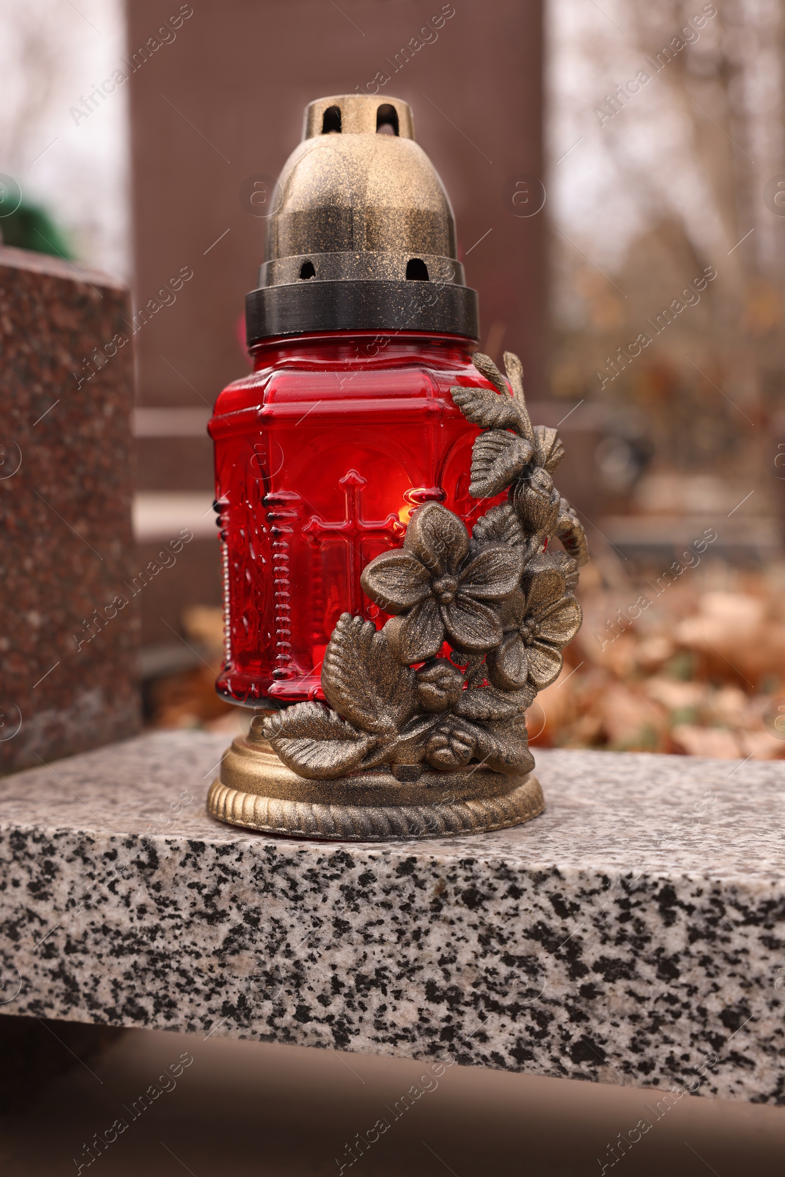 Photo of Grave lantern on grey granite surface at cemetery