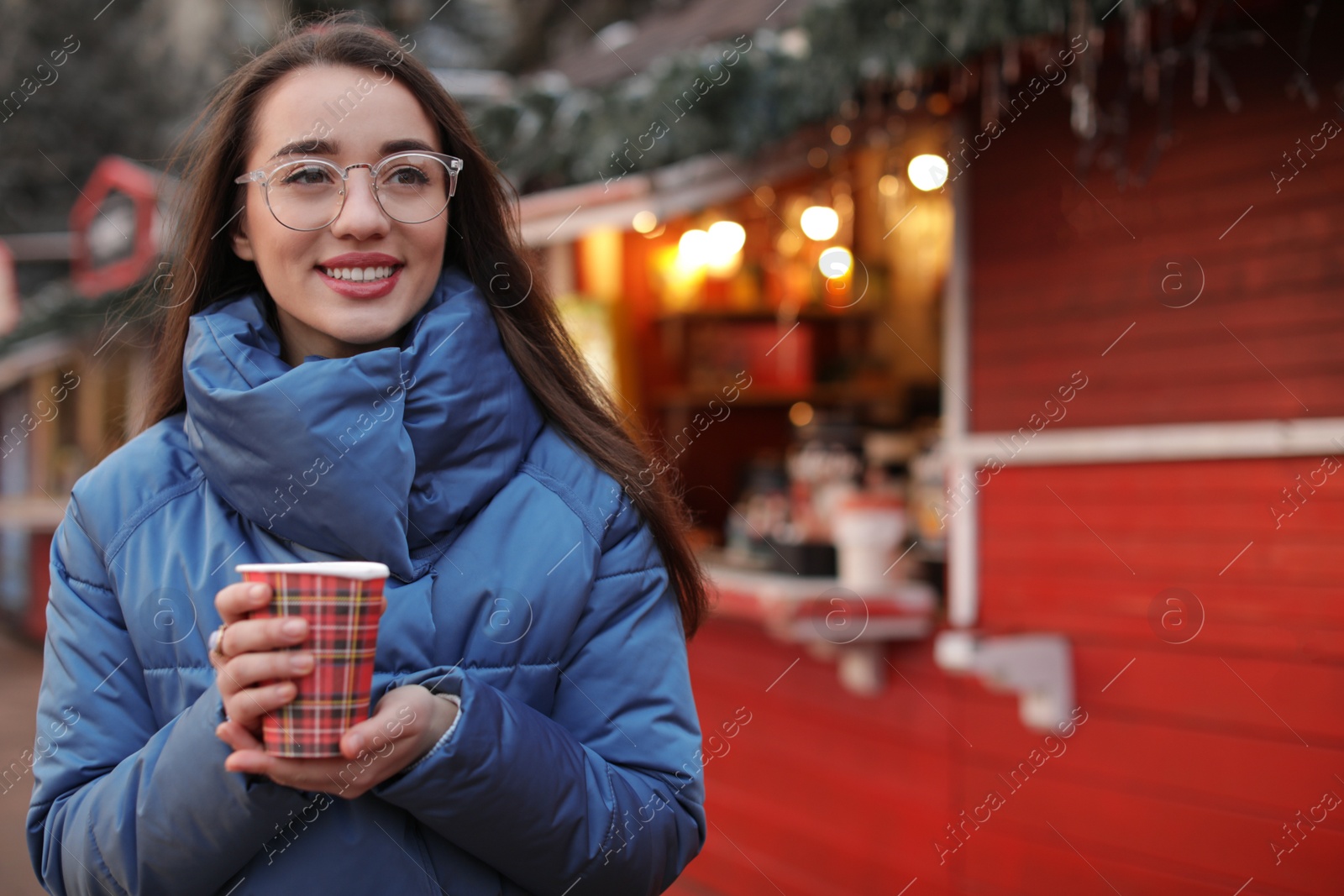 Photo of Woman with cup of mulled wine at winter fair. Space for text