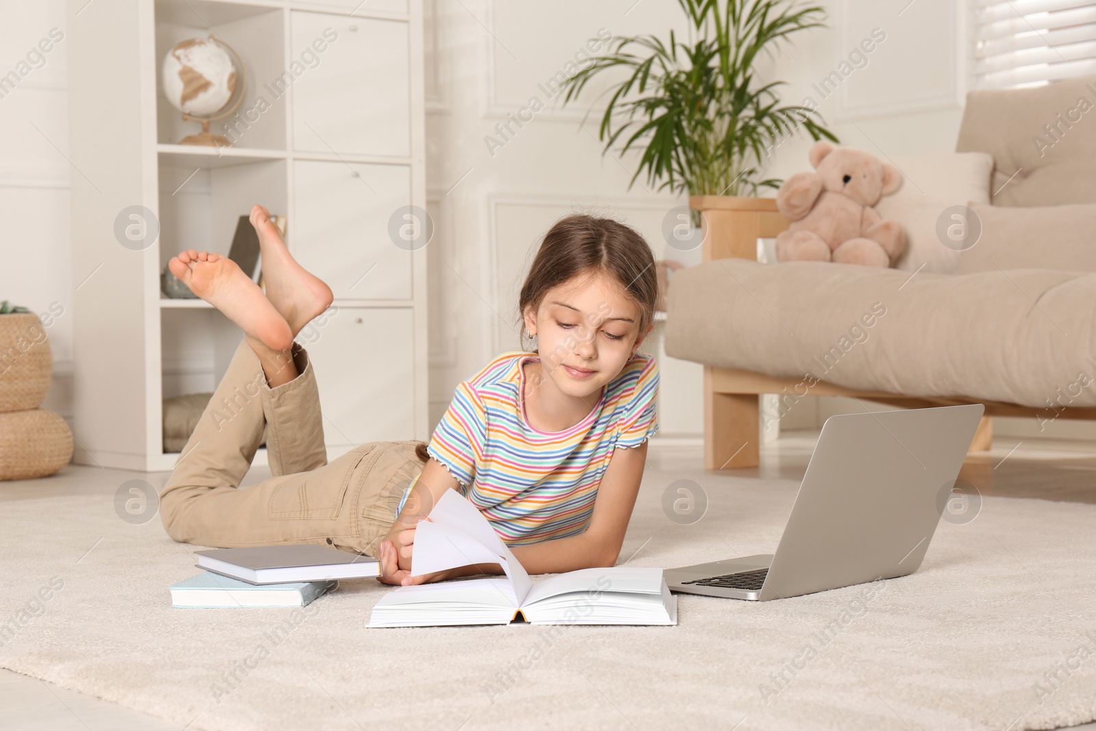 Photo of Girl with laptop and books lying on floor at home