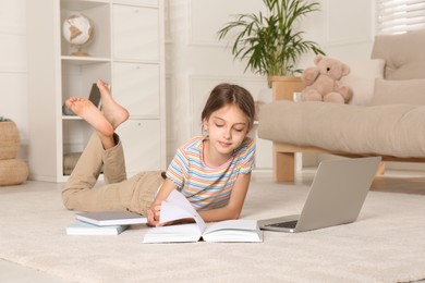 Photo of Girl with laptop and books lying on floor at home