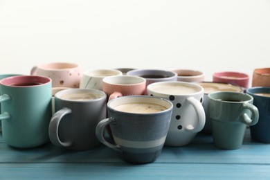 Photo of Many cups of different coffee drinks on light blue wooden table