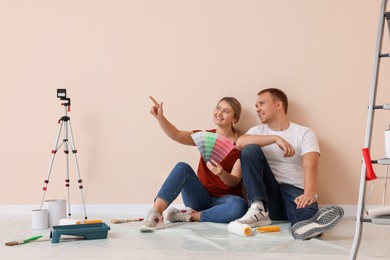 Photo of Couple with paint chips discussing new wall color in apartment during repair, space for text