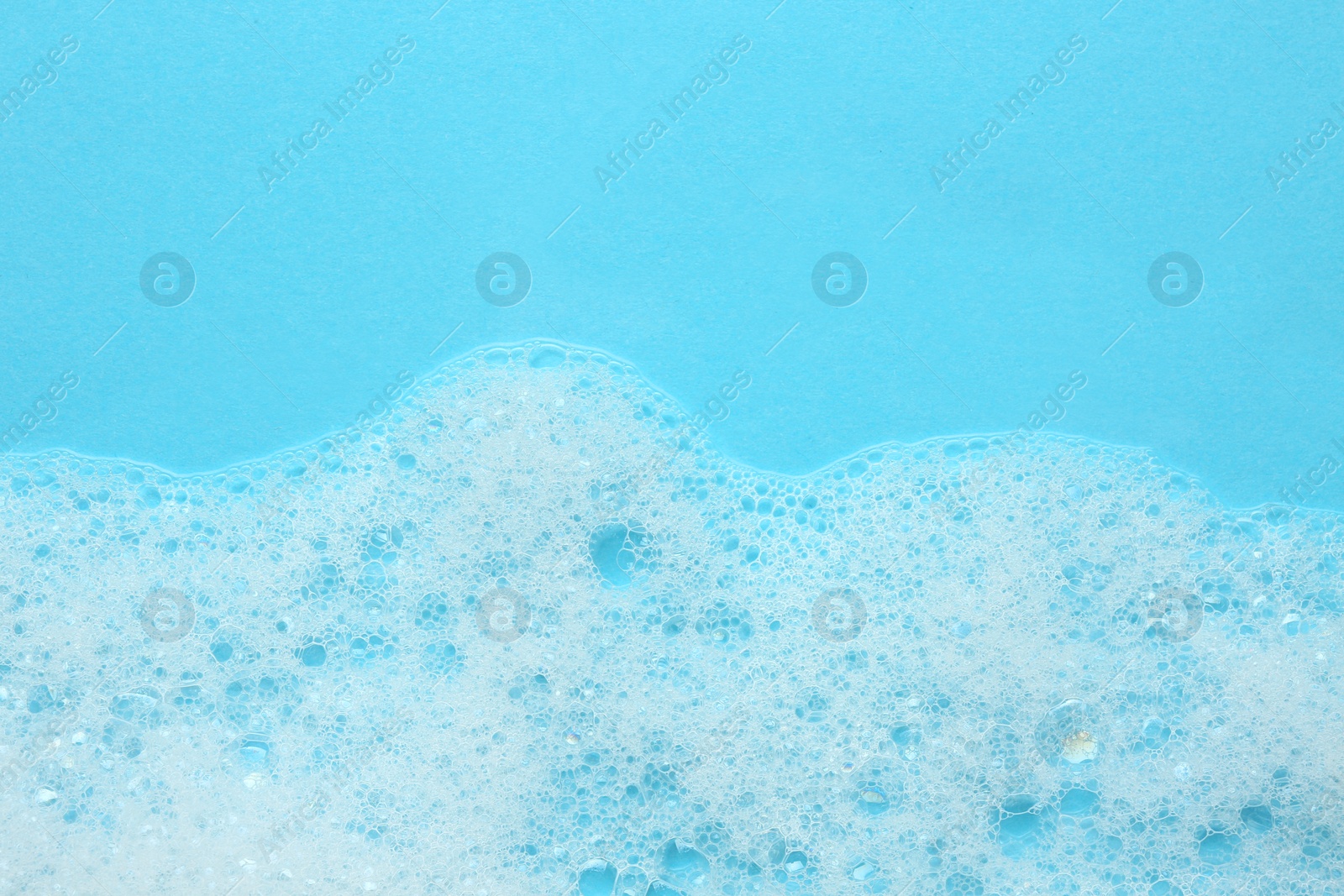 Photo of Fluffy bath foam on turquoise background, top view. Space for text