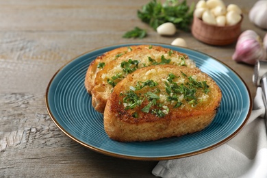 Slices of toasted bread with garlic and herb on wooden table