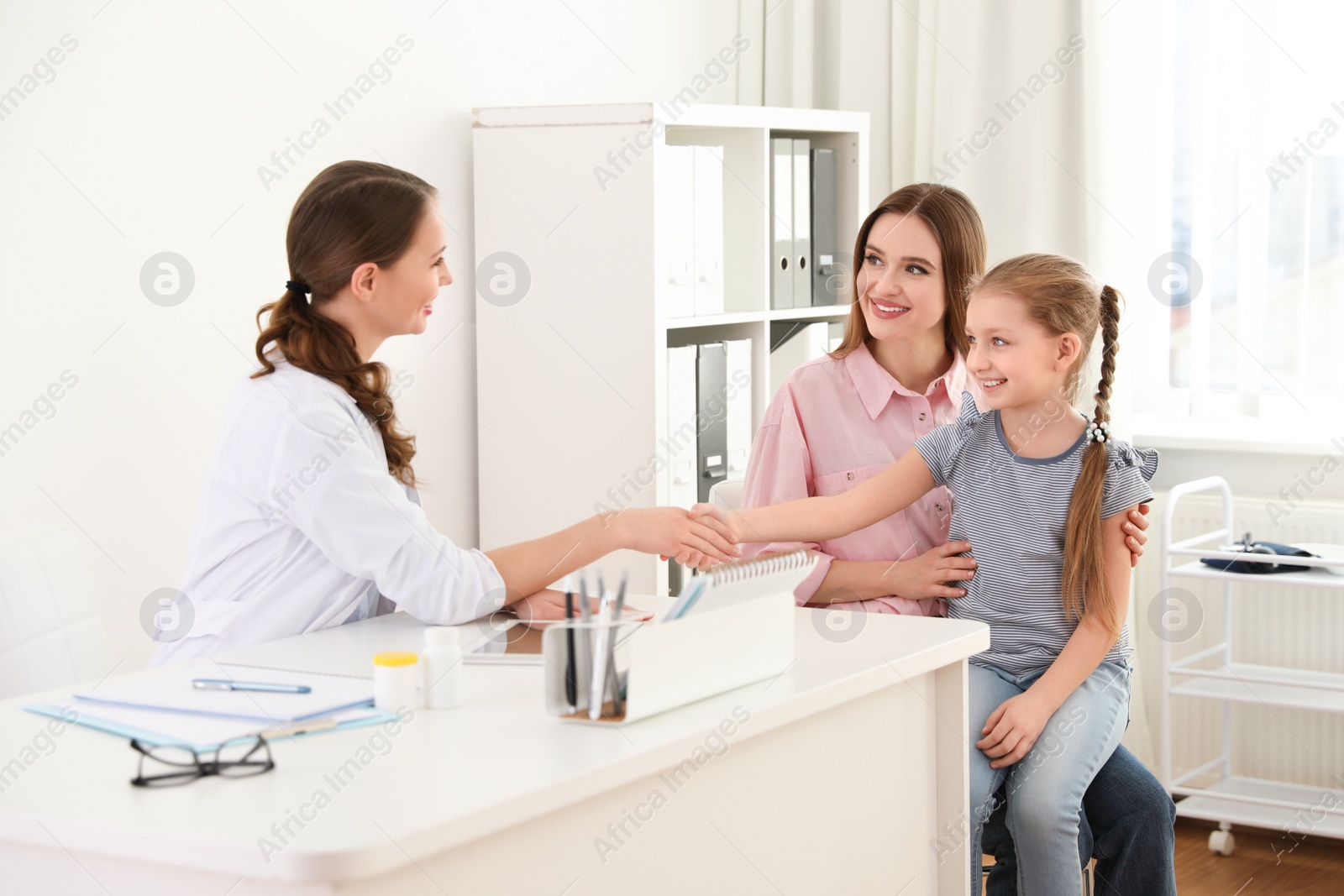 Photo of Mother and daughter visiting pediatrician. Doctor working with patient in hospital