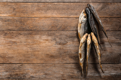 Photo of Dried fish hanging on rope against wooden background, space for text