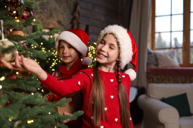 Happy children near beautiful Christmas tree at home