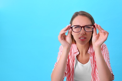 Young woman with vision problem wearing glasses on blue background