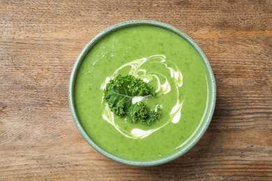 Photo of Tasty kale soup on wooden table, top view