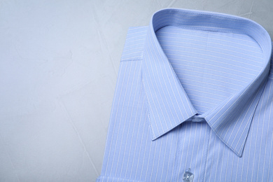 Photo of Stylish light blue shirt on grey background, top view with space for text. Dry-cleaning service