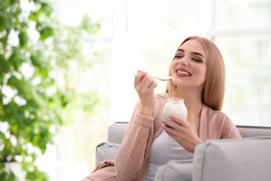 Photo of Young woman with yogurt indoors