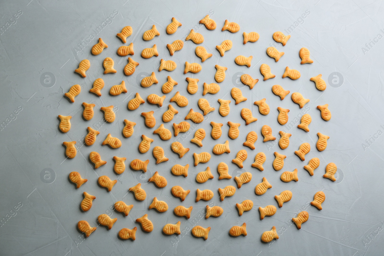 Photo of Delicious goldfish crackers on grey table, flat lay