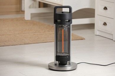 Modern infrared heater on floor in cozy room. Space for text