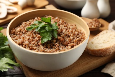 Photo of Tasty buckwheat with fresh parsley in bowl on table, closeup