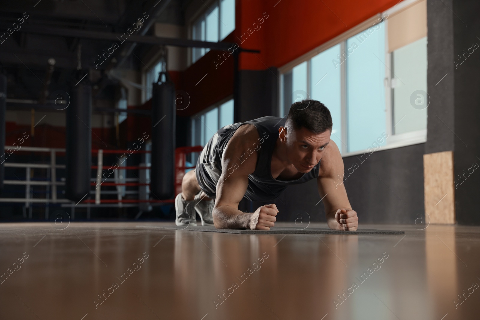 Photo of Man doing plank exercise in modern gym