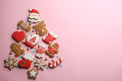Delicious gingerbread cookies arranged in shape of Christmas tree on pink background, flat lay. Space for text