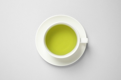 Cup of green tea on light background, top view