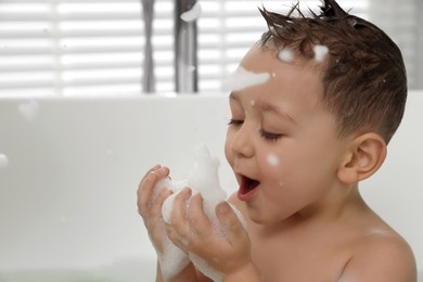 Photo of Cute little boy washing hair with shampoo in bathroom, closeup