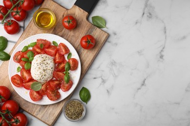 Photo of Tasty salad Caprese with mozarella, tomatoes, basil and other ingredients on white marble table, flat lay. Space for text