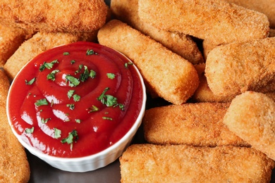 Photo of Tasty crispy cheese sticks and bowl of sauce, closeup