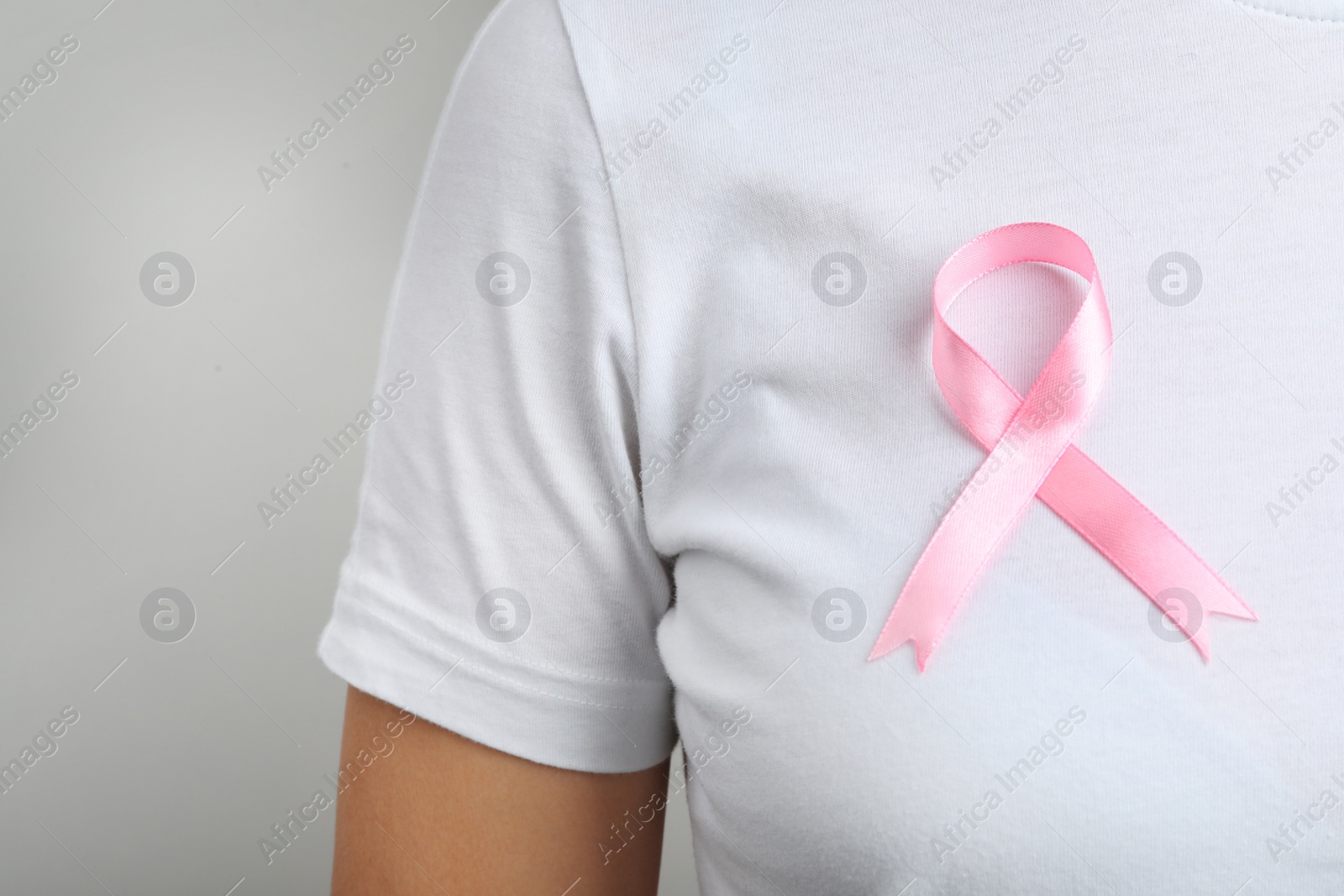 Photo of Woman with pink ribbon on grey background, space for text. Breast cancer awareness