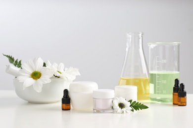 Photo of Skin care products, ingredients and laboratory glassware on table. Dermatology research